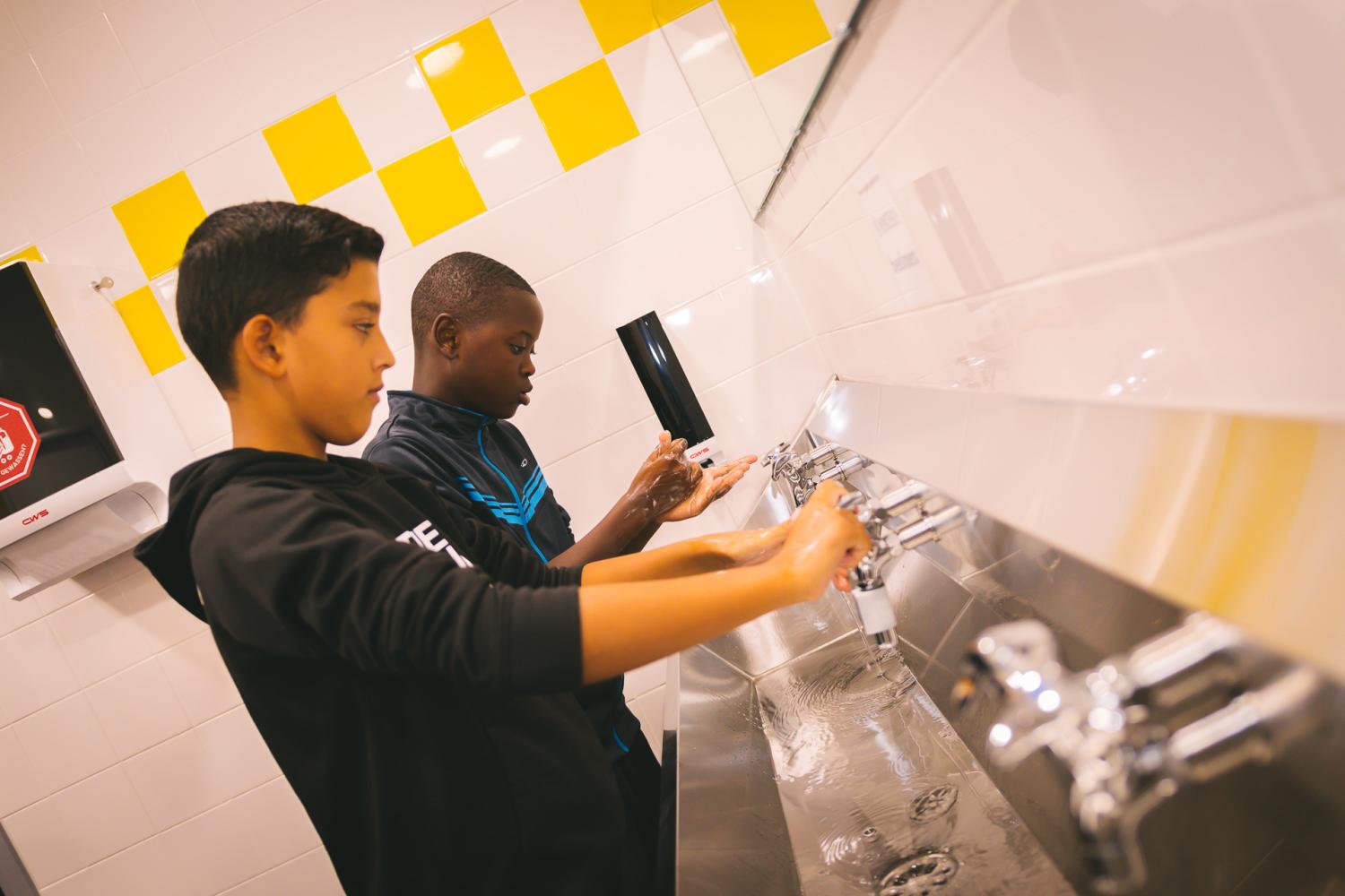 Seizoensgebonden scenario hygiëne, jongeren staan handen te wassen aan washbak