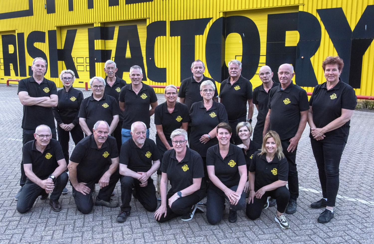 Groepsfoto van de begeleiders van Risk Factory Limburg-Noord voor het gele gebouw van de Risk Factory