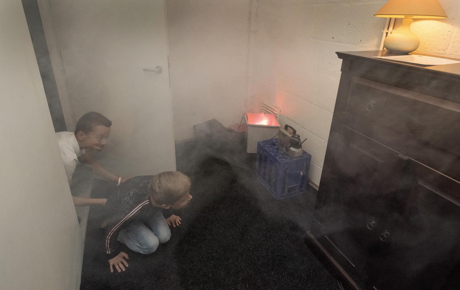 Kinderen beleven het scenario vluchten bij brand en kruipen laag over de vloer wordt een brand nagebootst in een woonkamer