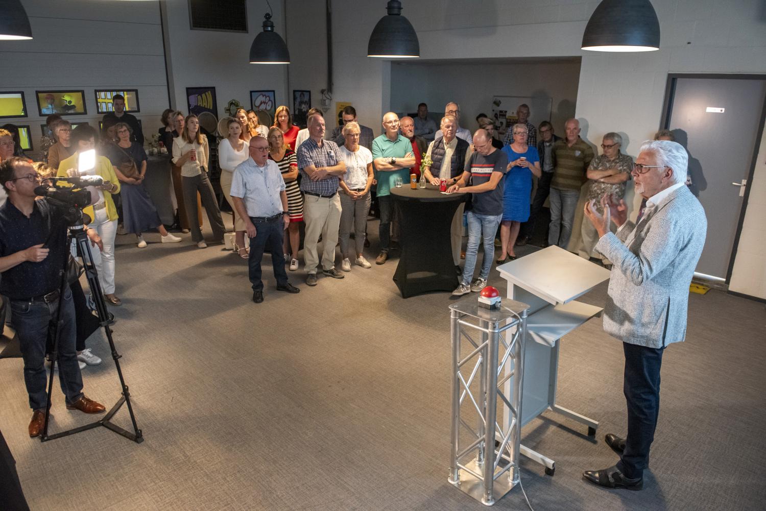 Man achter sprekersdesk spreekt een groep mensen toe in de Risk Factory