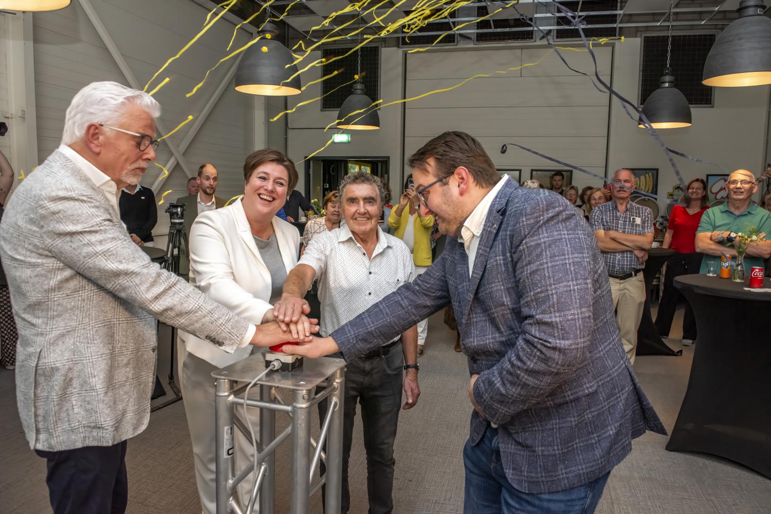 Vier personen duwen samen op een knop om scenario te openen, waarbij er confetti door de lucht vliegt