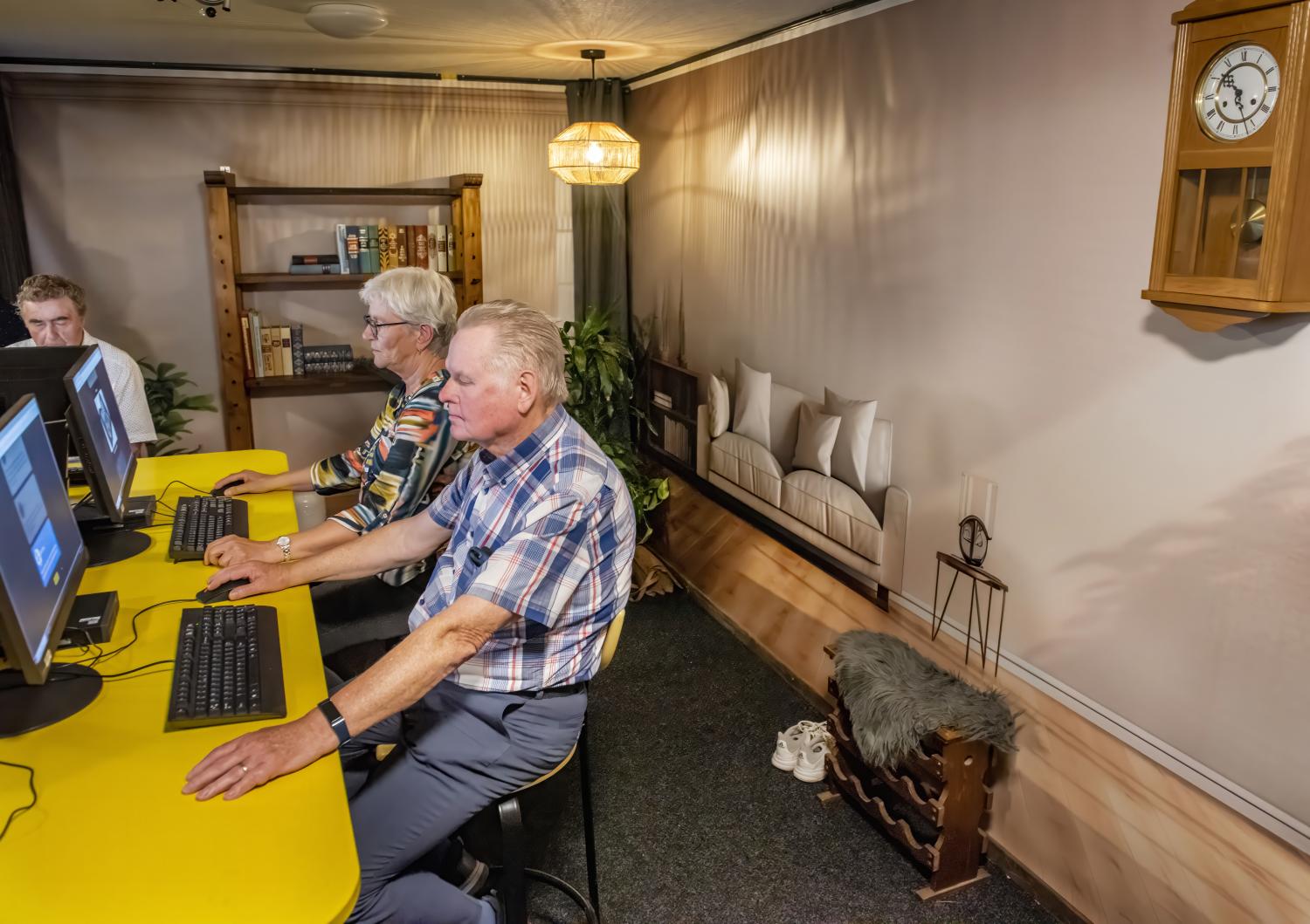 Twee senioren zitten beide achter de computer in de Risk Factory