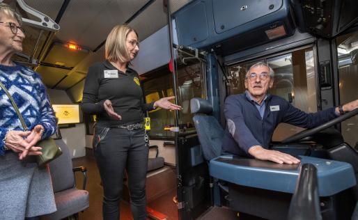 Senioren die in de bus zitten en uitleg krijgen over de dode hoek door begeleider