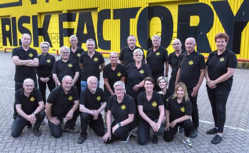 Groepsfoto van de begeleiders van Risk Factory Limburg-Noord voor het gele gebouw van de Risk Factory